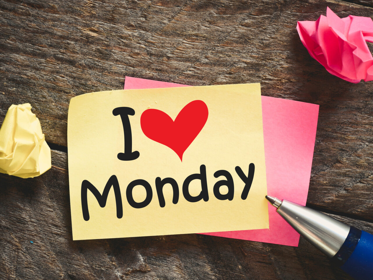 Note with I love Monday and red heart on the wooden background with pen
